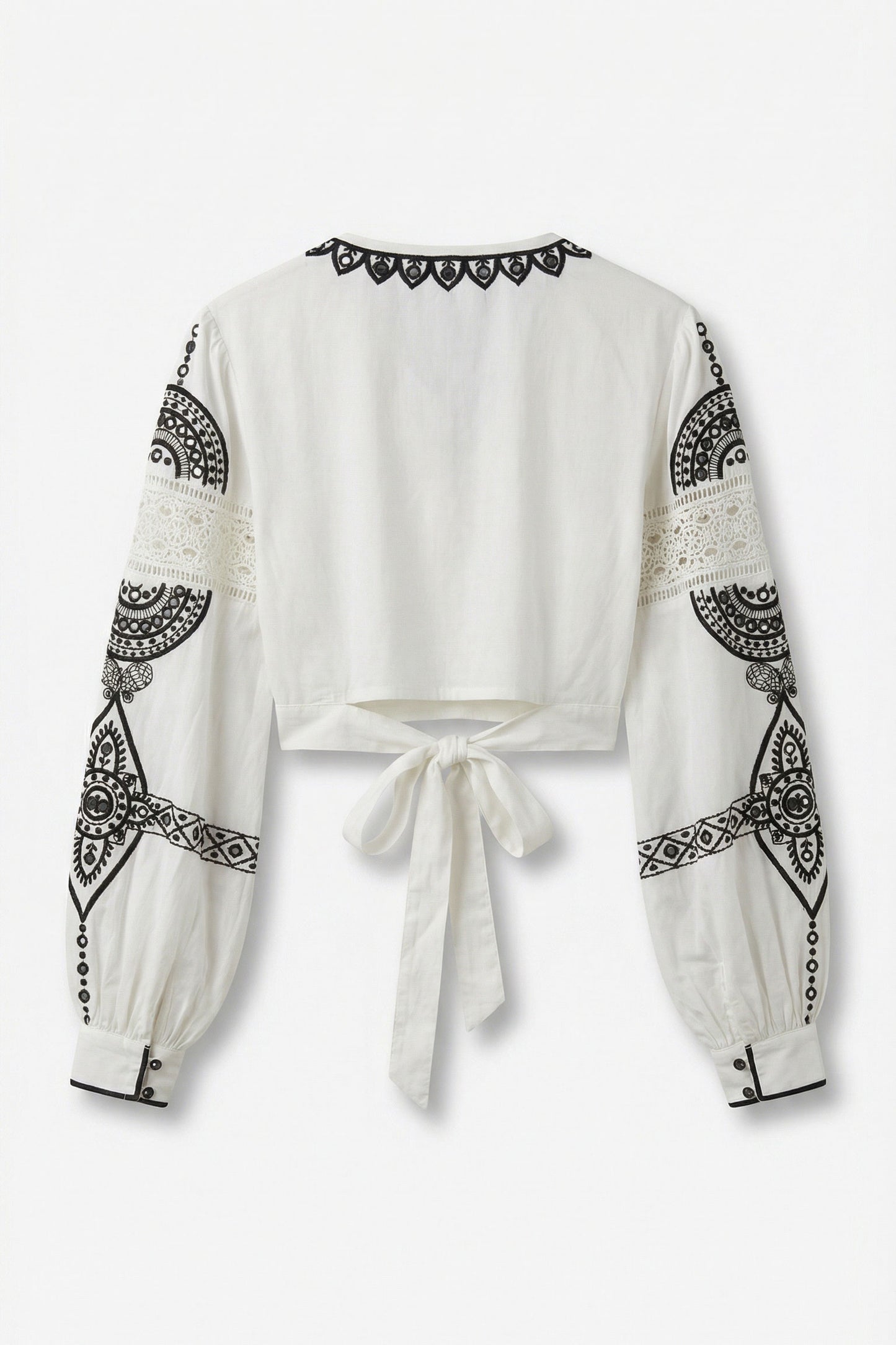 White blouse with black geometric patterns on sleeves and neckline against a white background