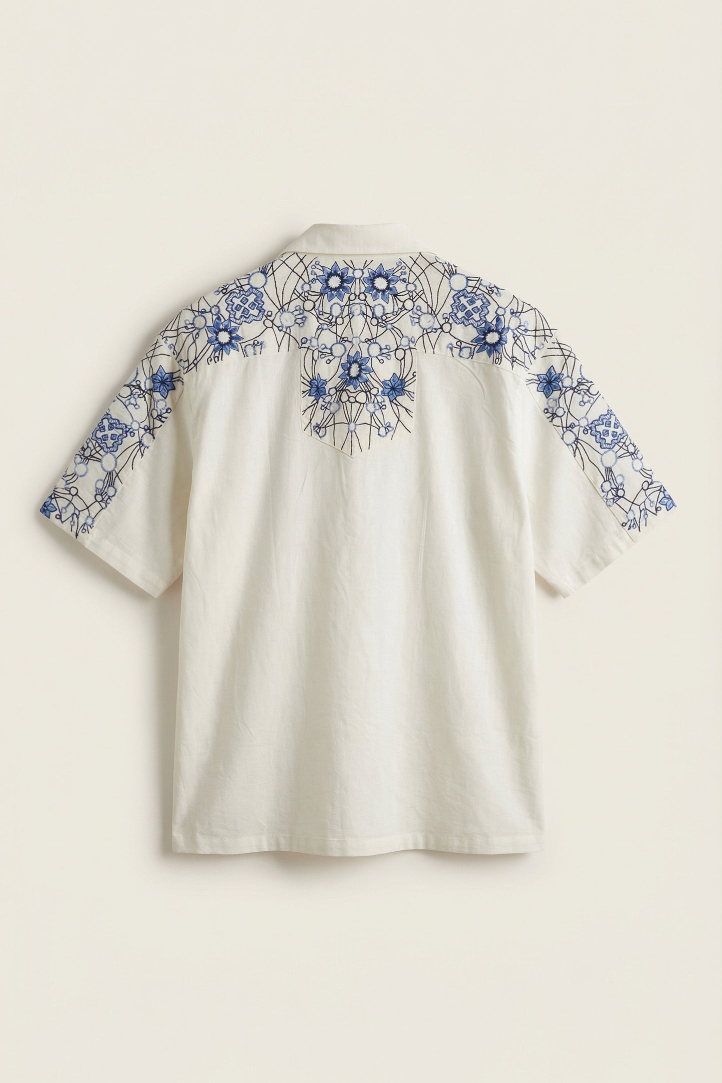 White blouse with blue floral embroidery on a beige background