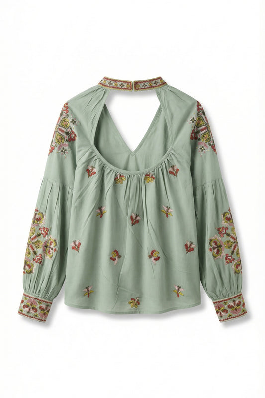 Green blouse with floral embroidery on a white background
