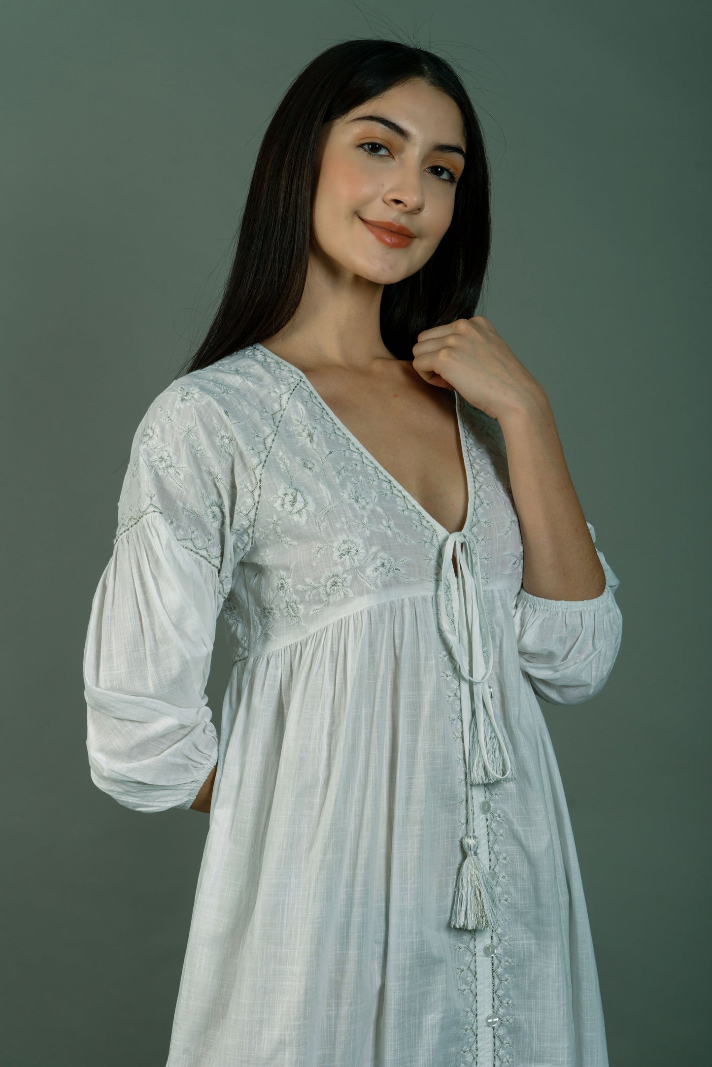 Woman wearing a white lace dress against a gray background