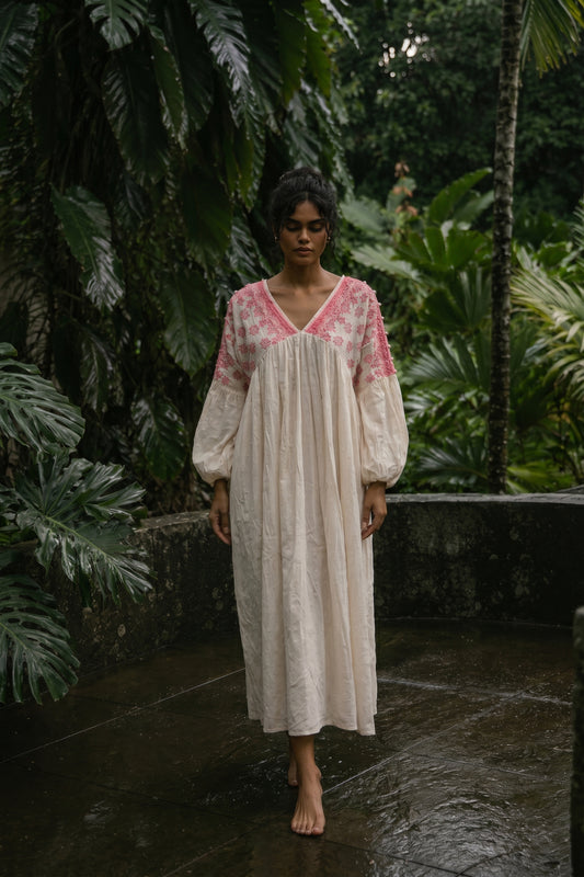 Woman in a white dress with pink accents standing in a tropical setting