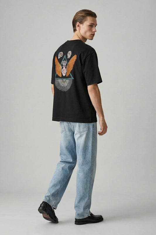 Person wearing a black t-shirt with a colorful design on the back, standing against a plain background.