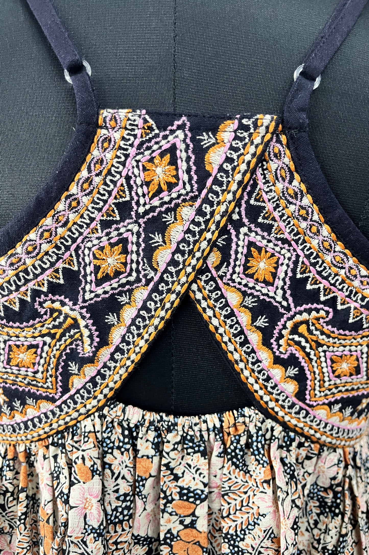 Close-up of a patterned top with floral and paisley designs on a dark background