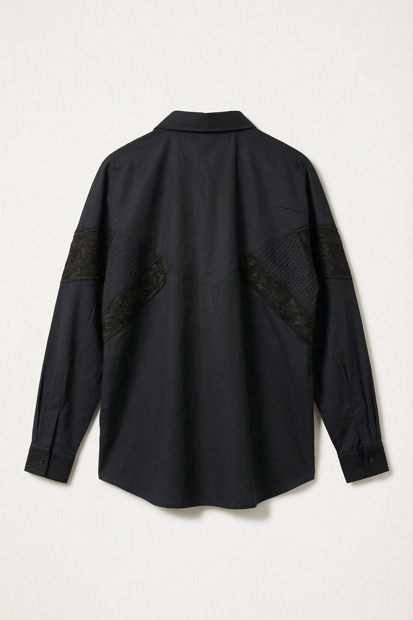 Black shirt with patch details on a light gray background