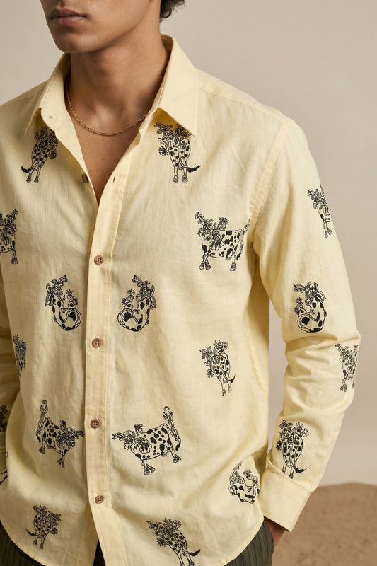 Man wearing a light yellow shirt with black animal prints on a neutral background