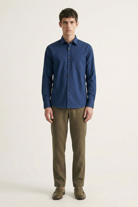 Man wearing a blue shirt and brown pants on a white background