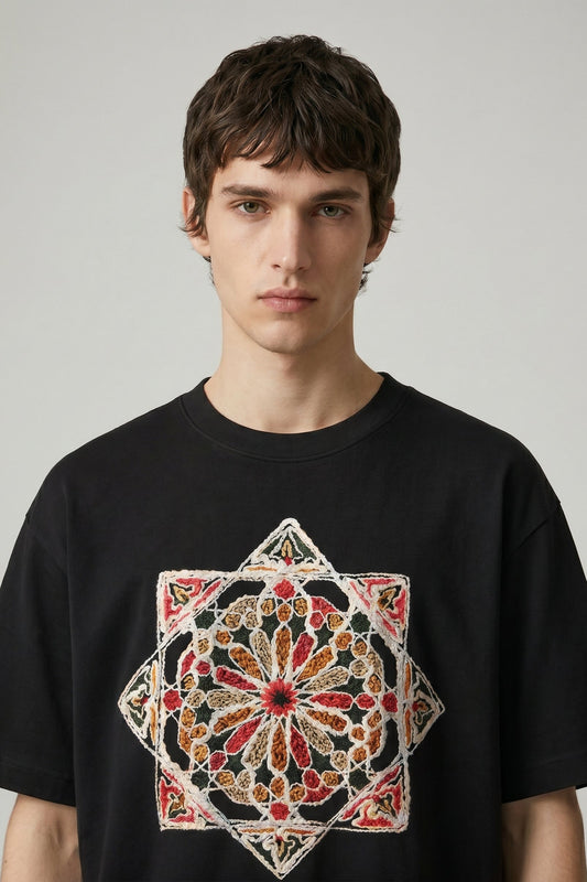 Man wearing a black t-shirt with a colorful geometric design on a plain background