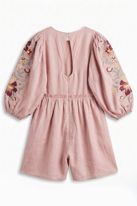 Pink romper with floral embroidery on sleeves and back, on a white background