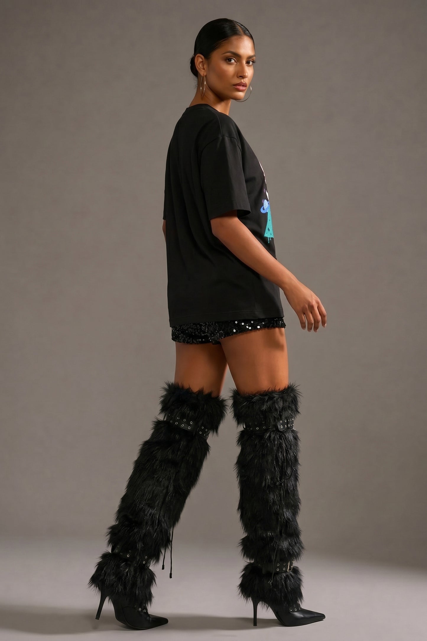 Woman wearing a black outfit with feathered boots on a gray background