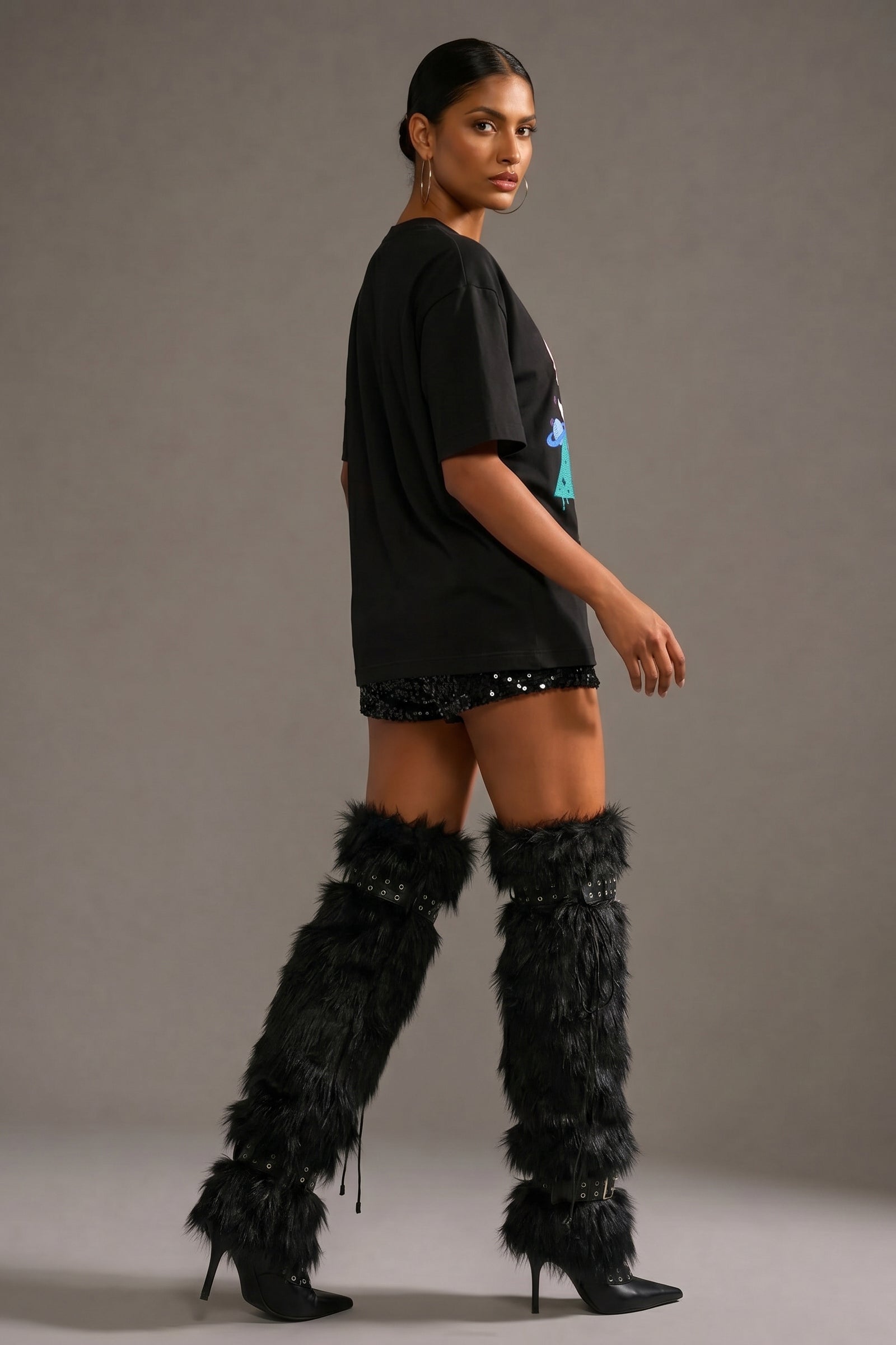 Woman wearing a black outfit with feathered boots on a gray background