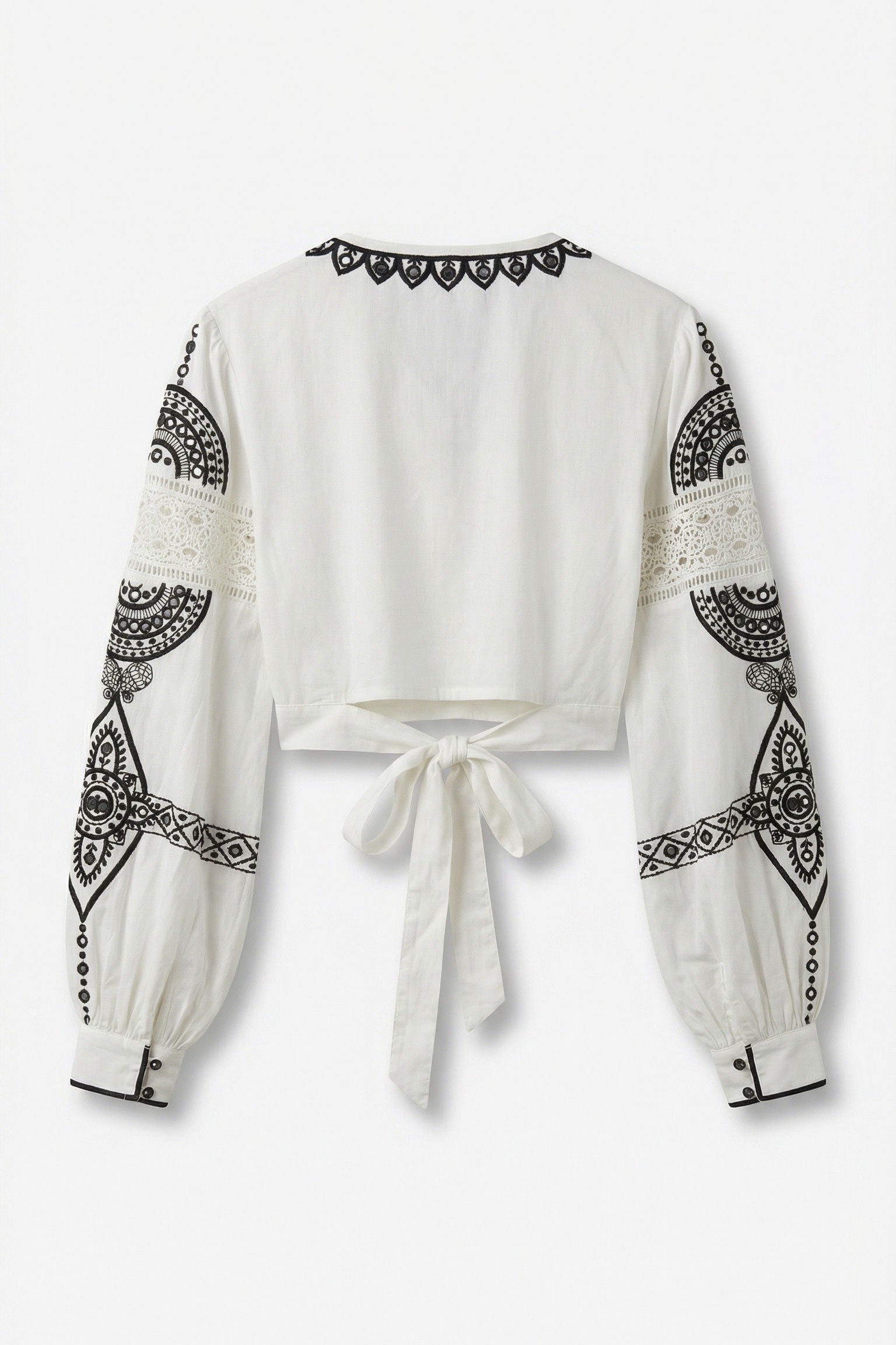White blouse with black geometric patterns on sleeves and neckline against a white background