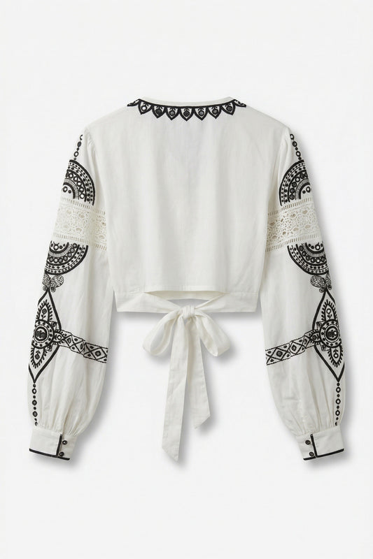 White blouse with black geometric patterns on sleeves and neckline against a white background
