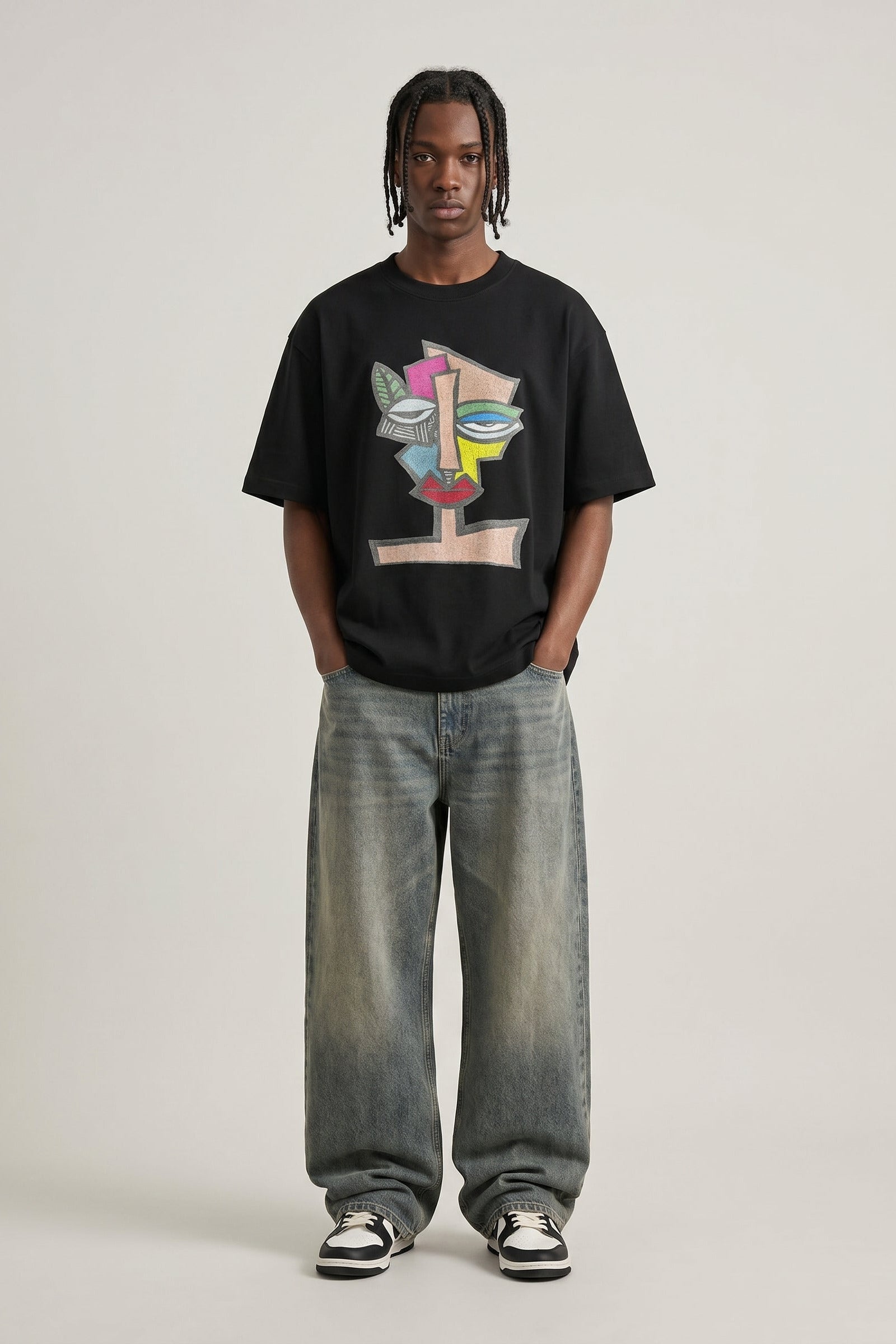 Person wearing a black t-shirt with colorful design and light blue jeans on a white background