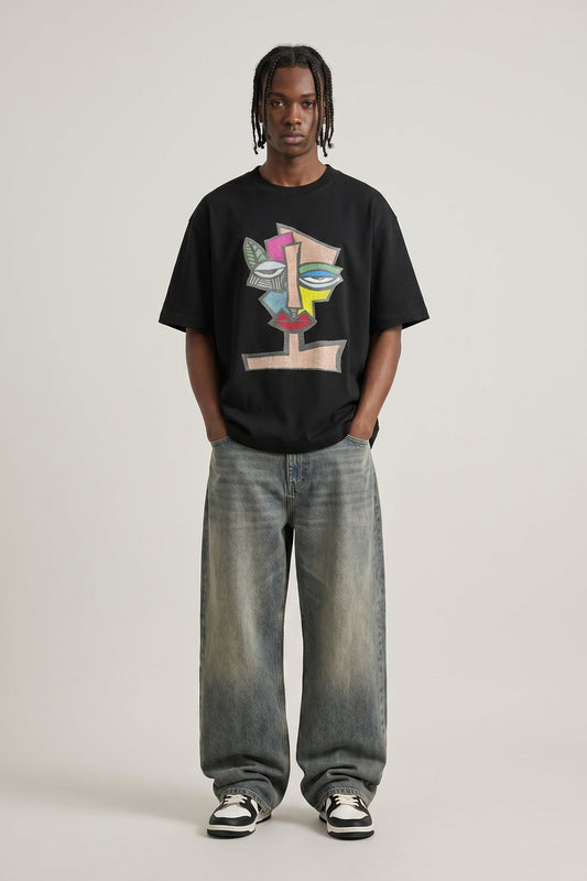 Person wearing a black t-shirt with colorful design and light blue jeans on a white background