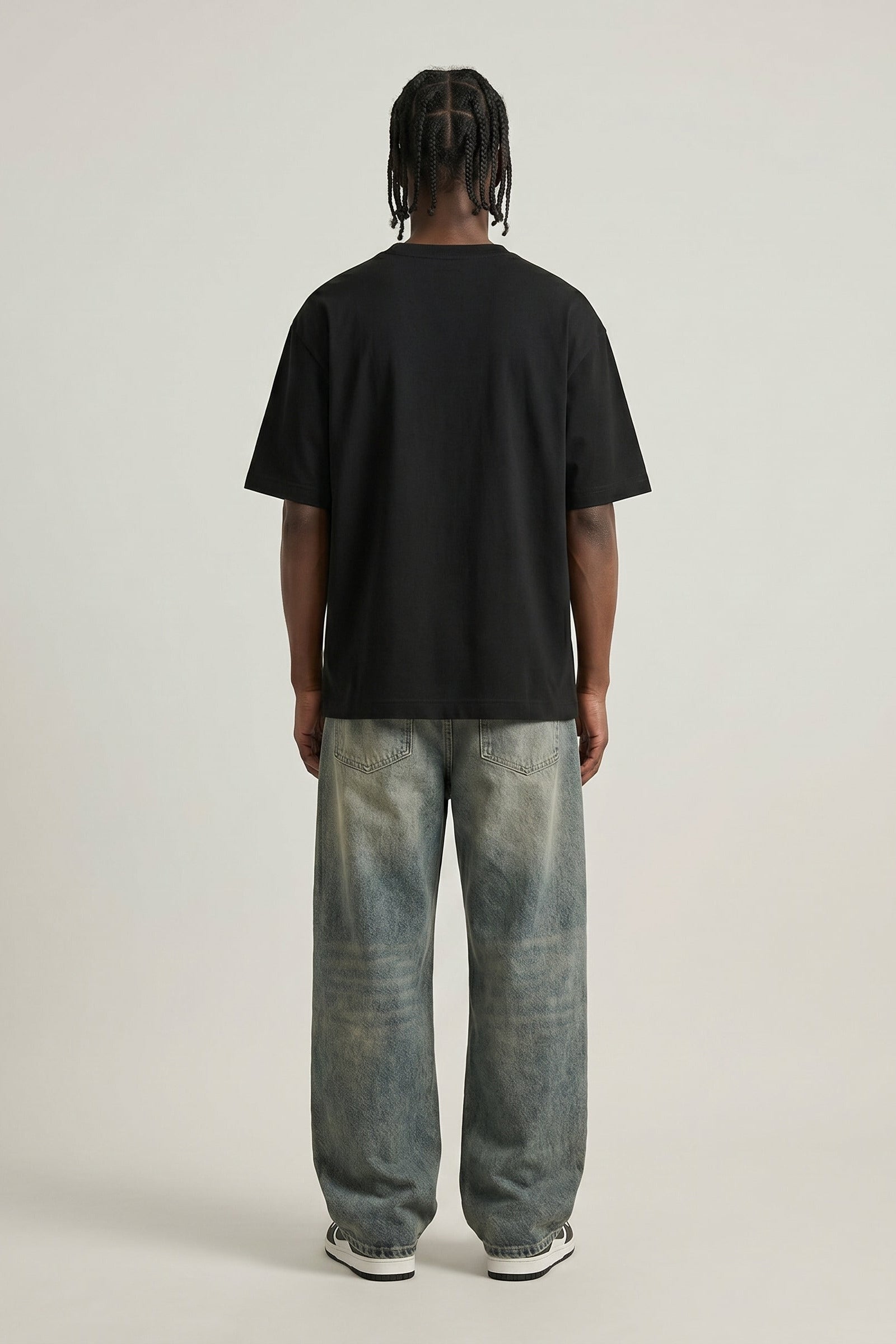 Person wearing a black t-shirt and light blue jeans on a plain background
