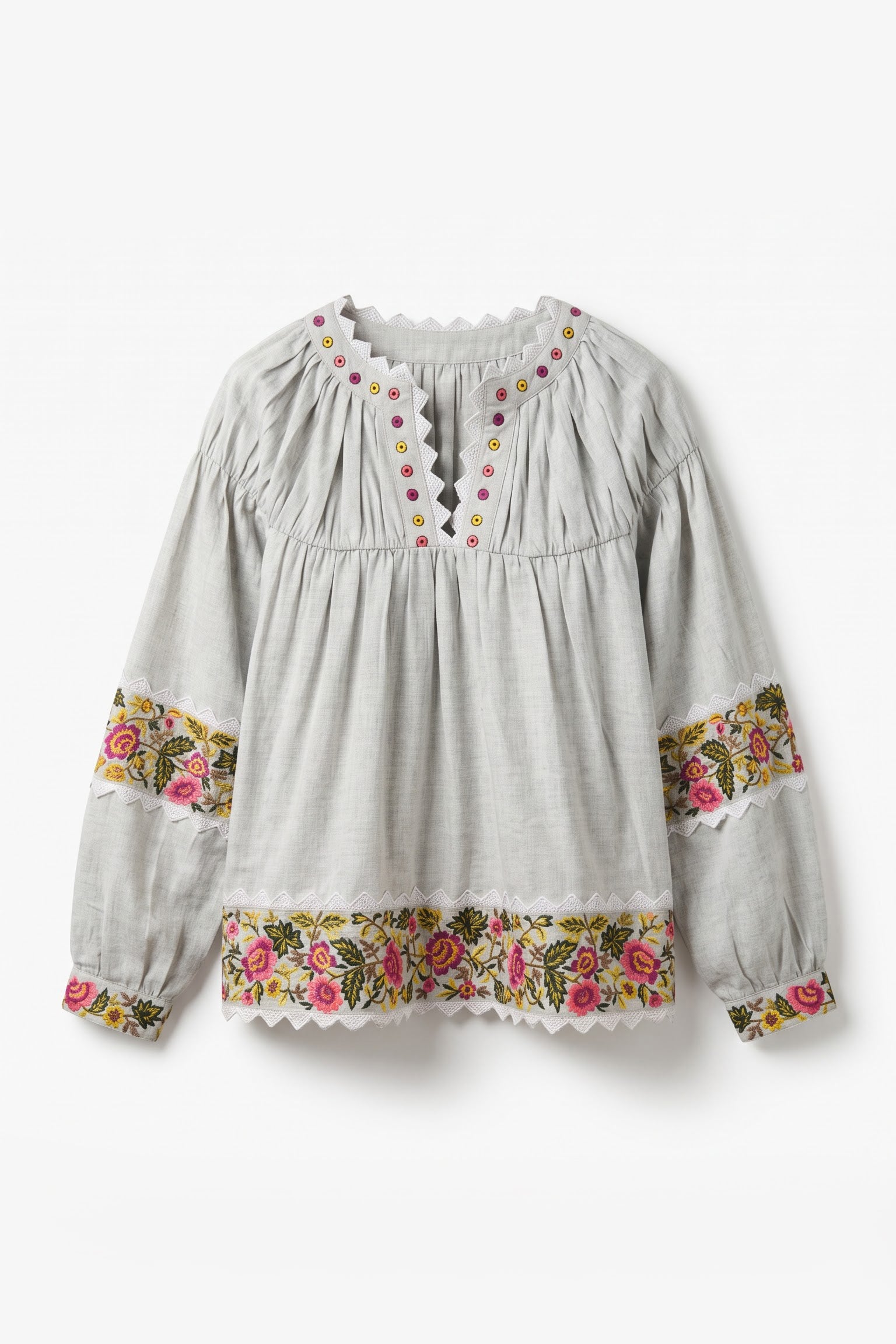A light gray long-sleeve blouse with a gathered smocked bodice, scalloped neckline, and floral embroidered trim on the cuffs and hem.