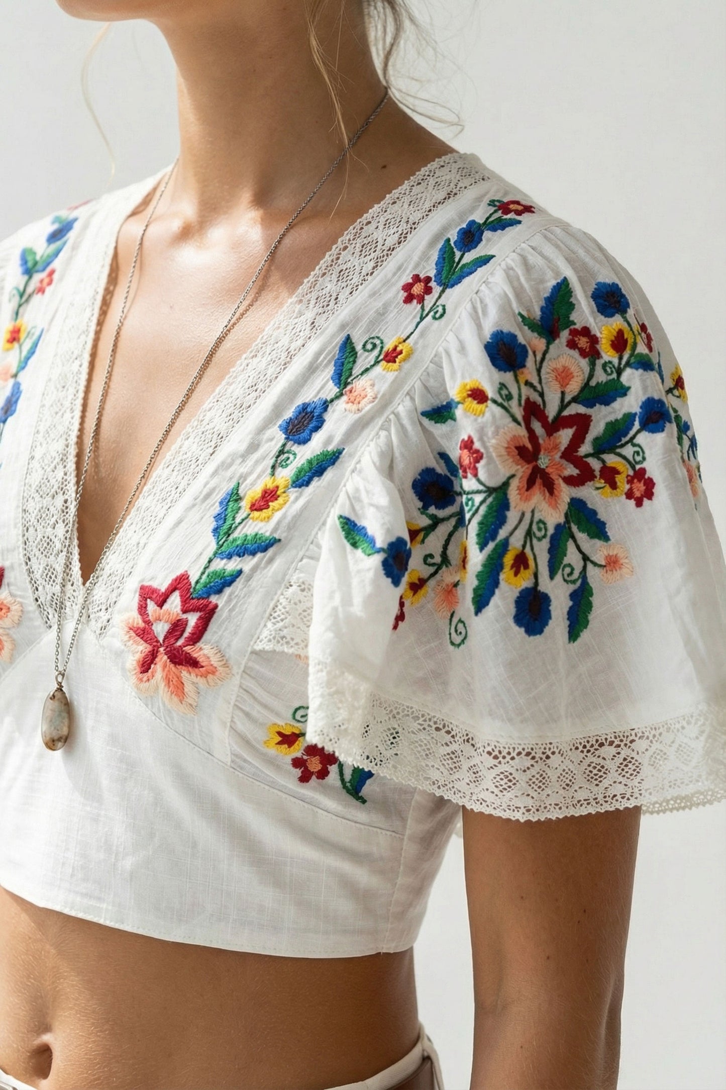 White blouse with colorful floral embroidery on a plain background