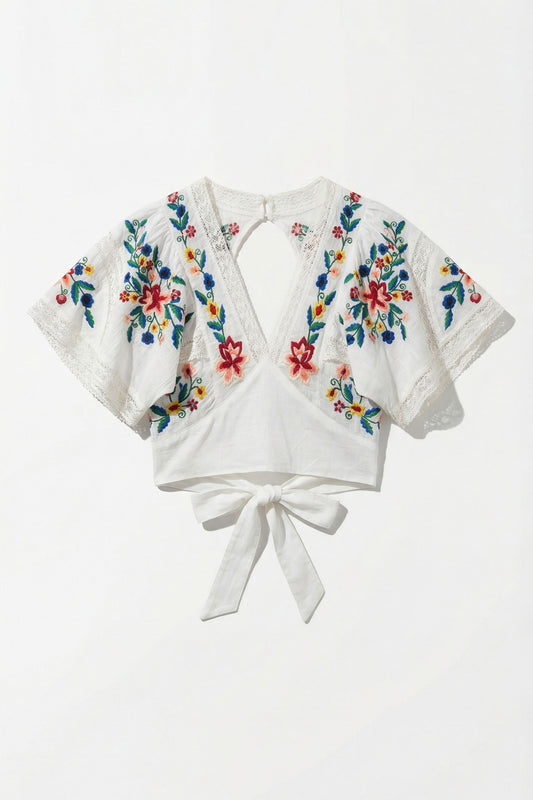 White blouse with colorful floral embroidery on a white background