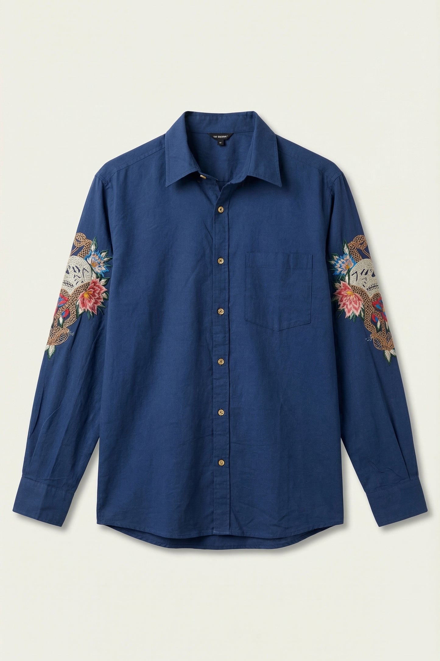 Blue shirt with floral patterns on sleeves against a beige background