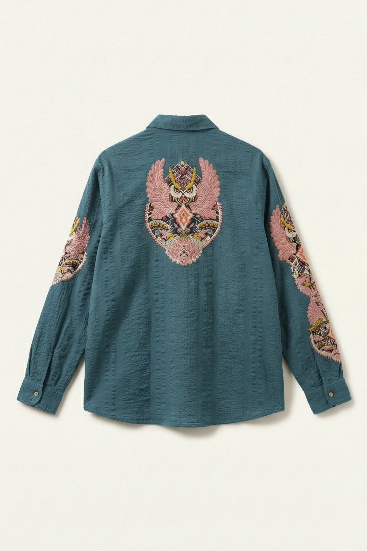 Teal shirt with floral embroidery on sleeves and back against a white background