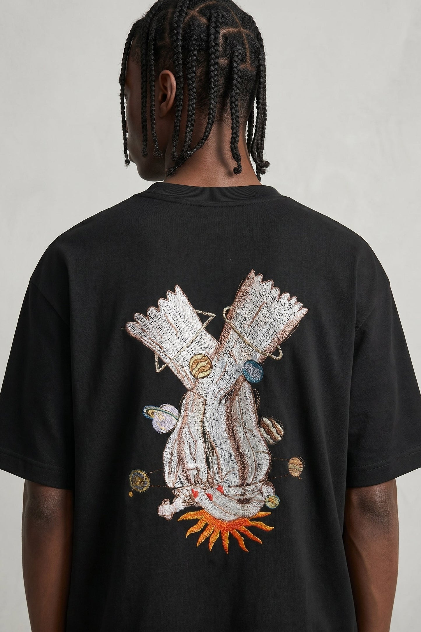 Person wearing a black t-shirt with a colorful graphic design on the back against a plain background