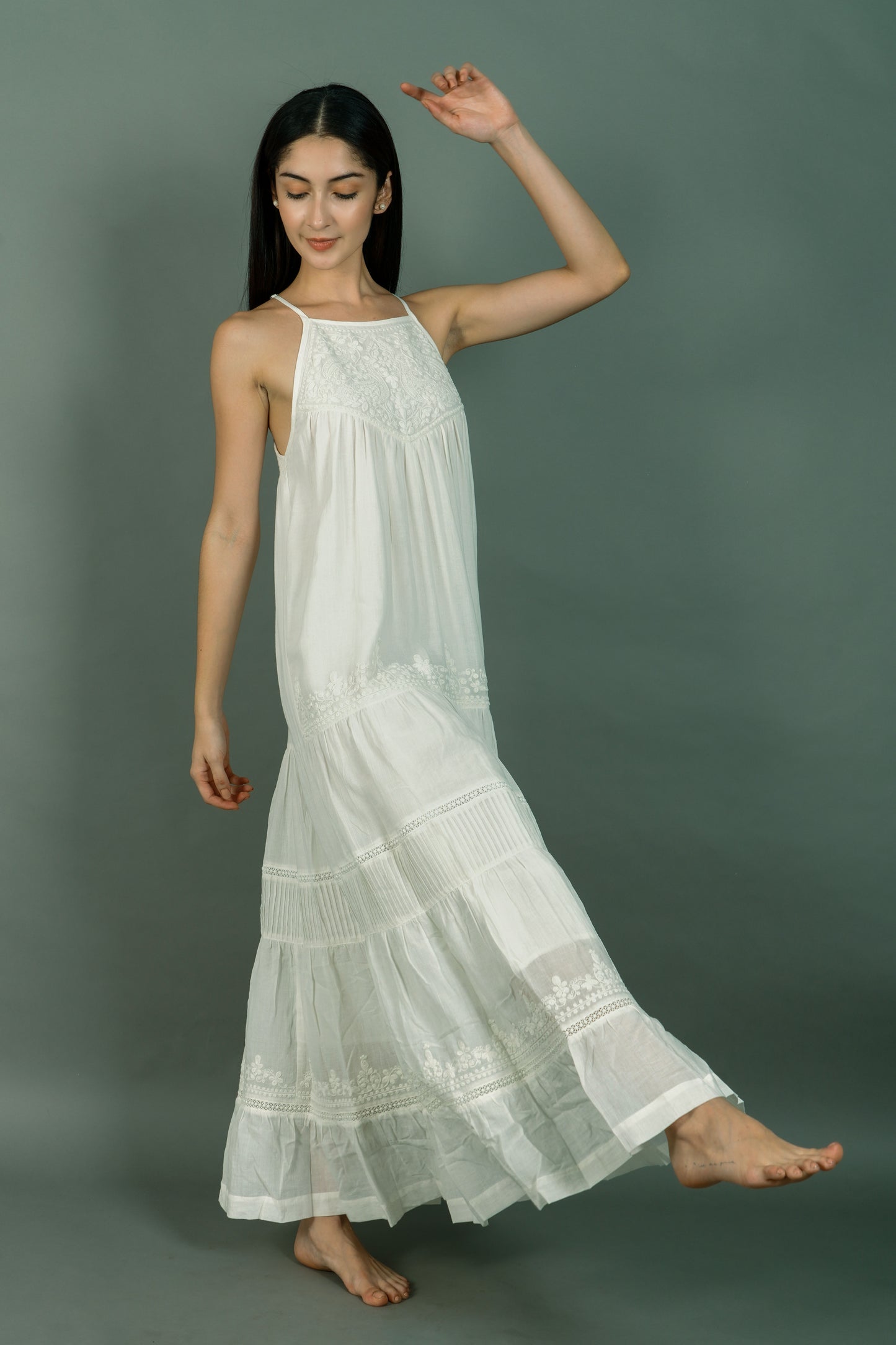 Woman wearing a white dress with lace details on a plain background