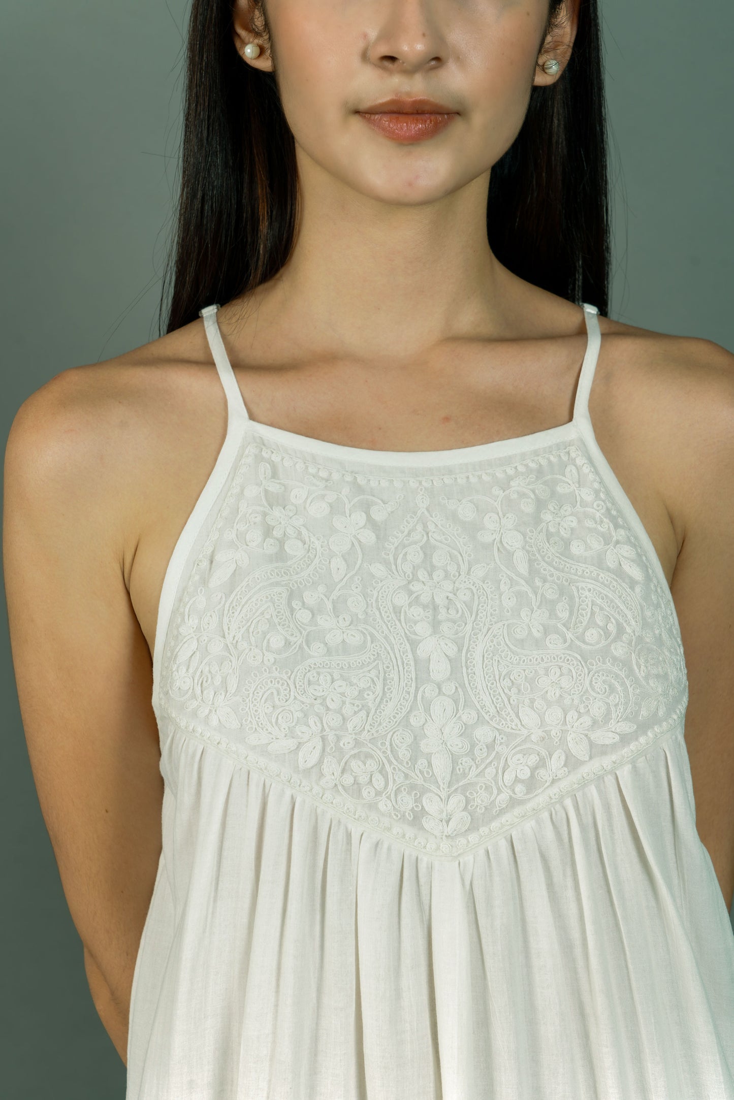Woman wearing a white lace dress against a gray background