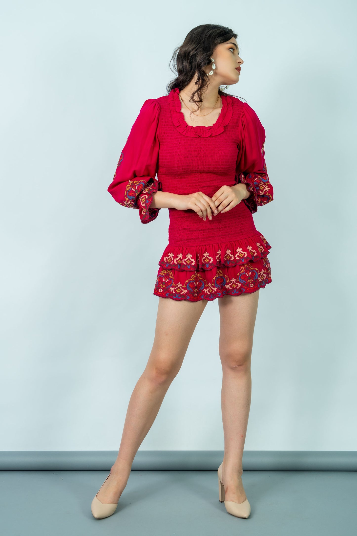 Woman wearing a red outfit with floral embroidery on a light blue background