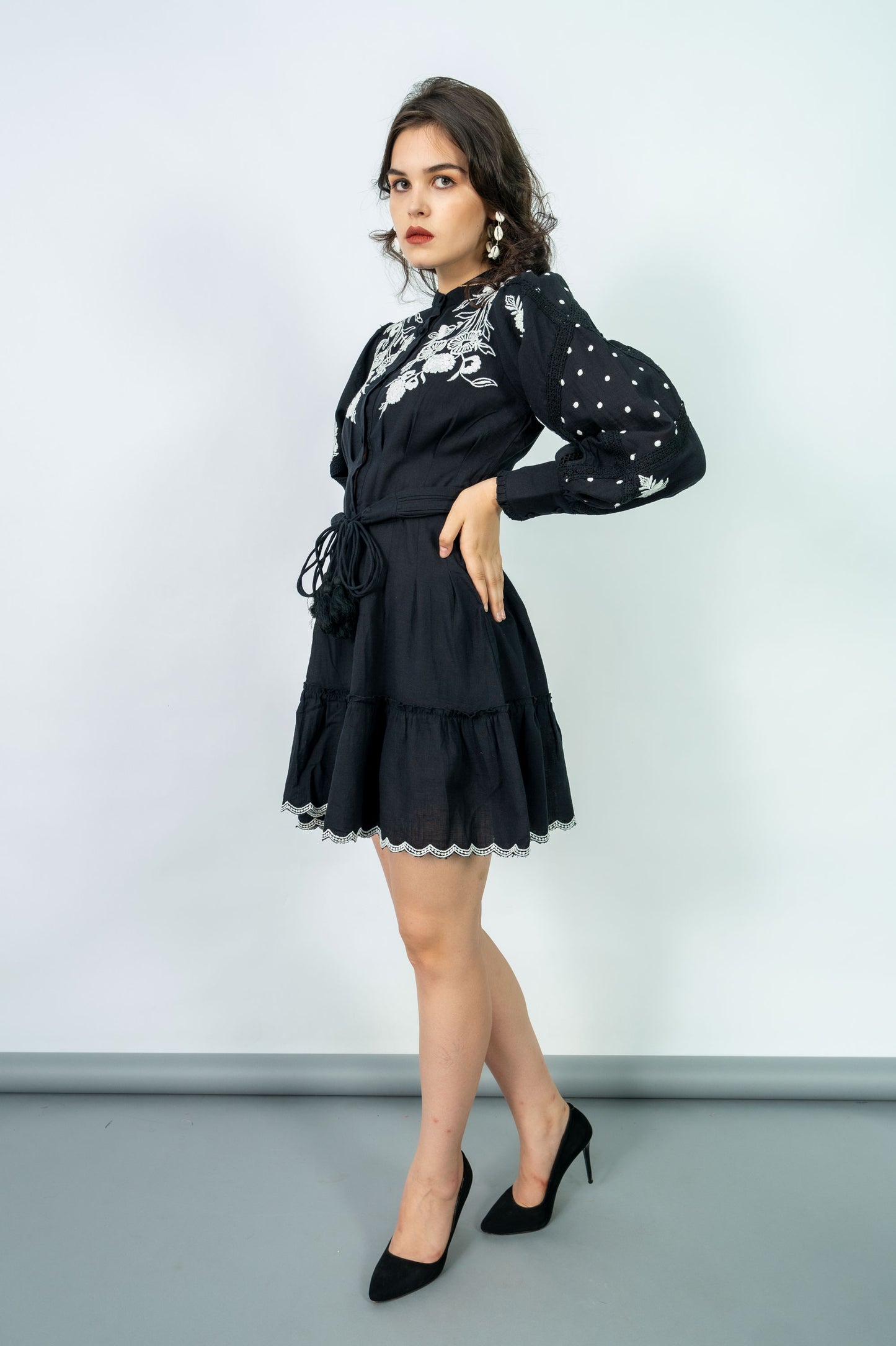 Woman wearing a black dress with white floral patterns against a light gray background