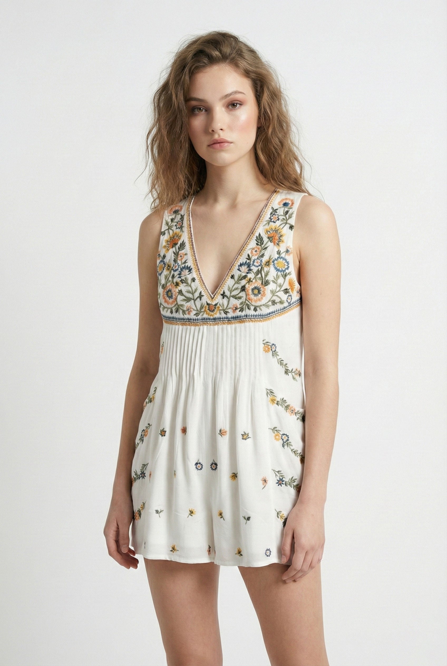 Woman wearing a white dress with floral embroidery on a white background