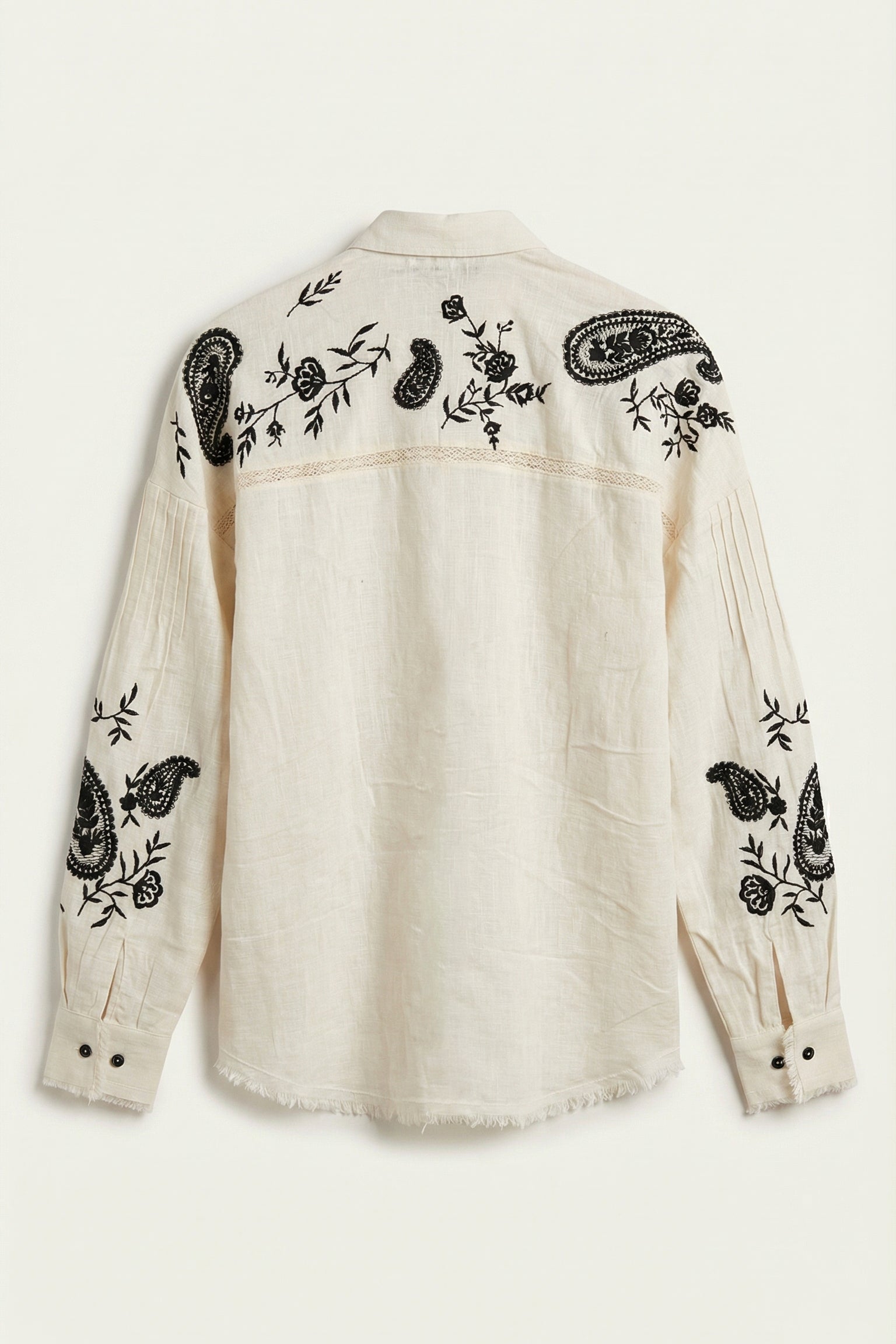 White shirt with black floral and paisley embroidery on a white background