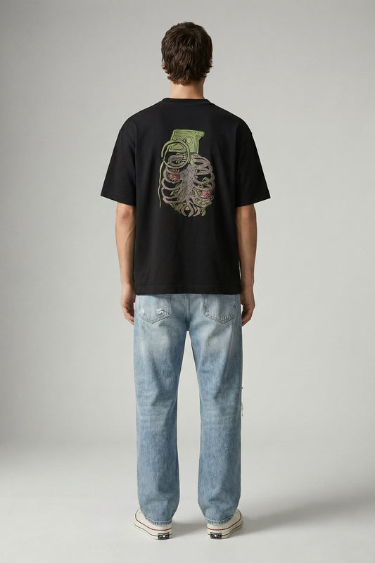 Person wearing a black t-shirt with a graphic design on the back and light blue jeans, standing against a plain background.