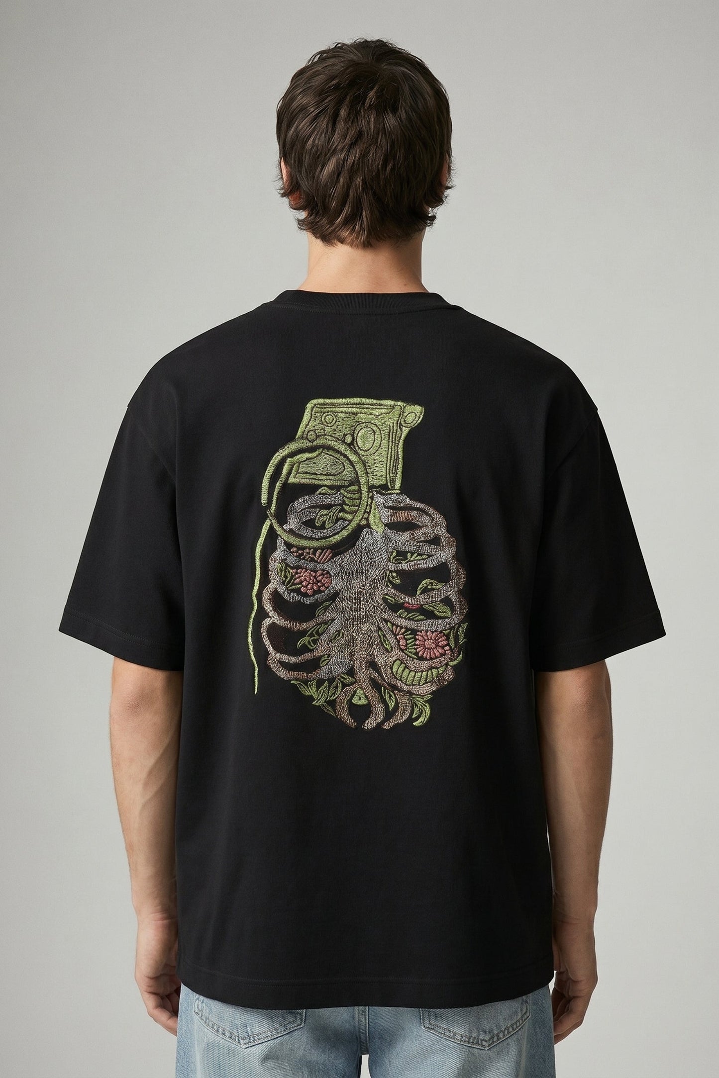 Person wearing a black t-shirt with a graphic design on the back against a gray background