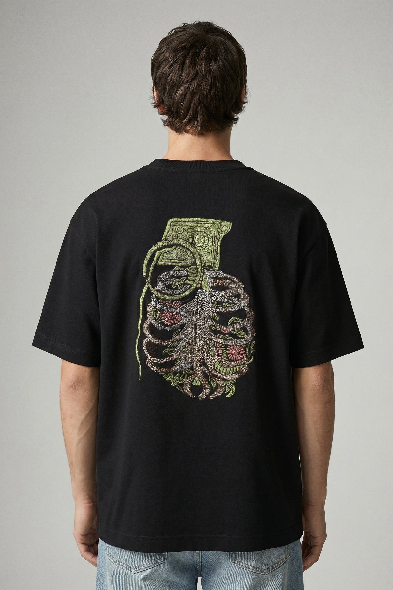 Person wearing a black t-shirt with a graphic design on the back against a gray background