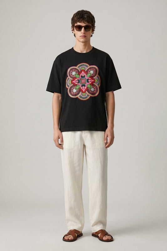 Person wearing a black t-shirt with a colorful flower design and white pants on a gray background
