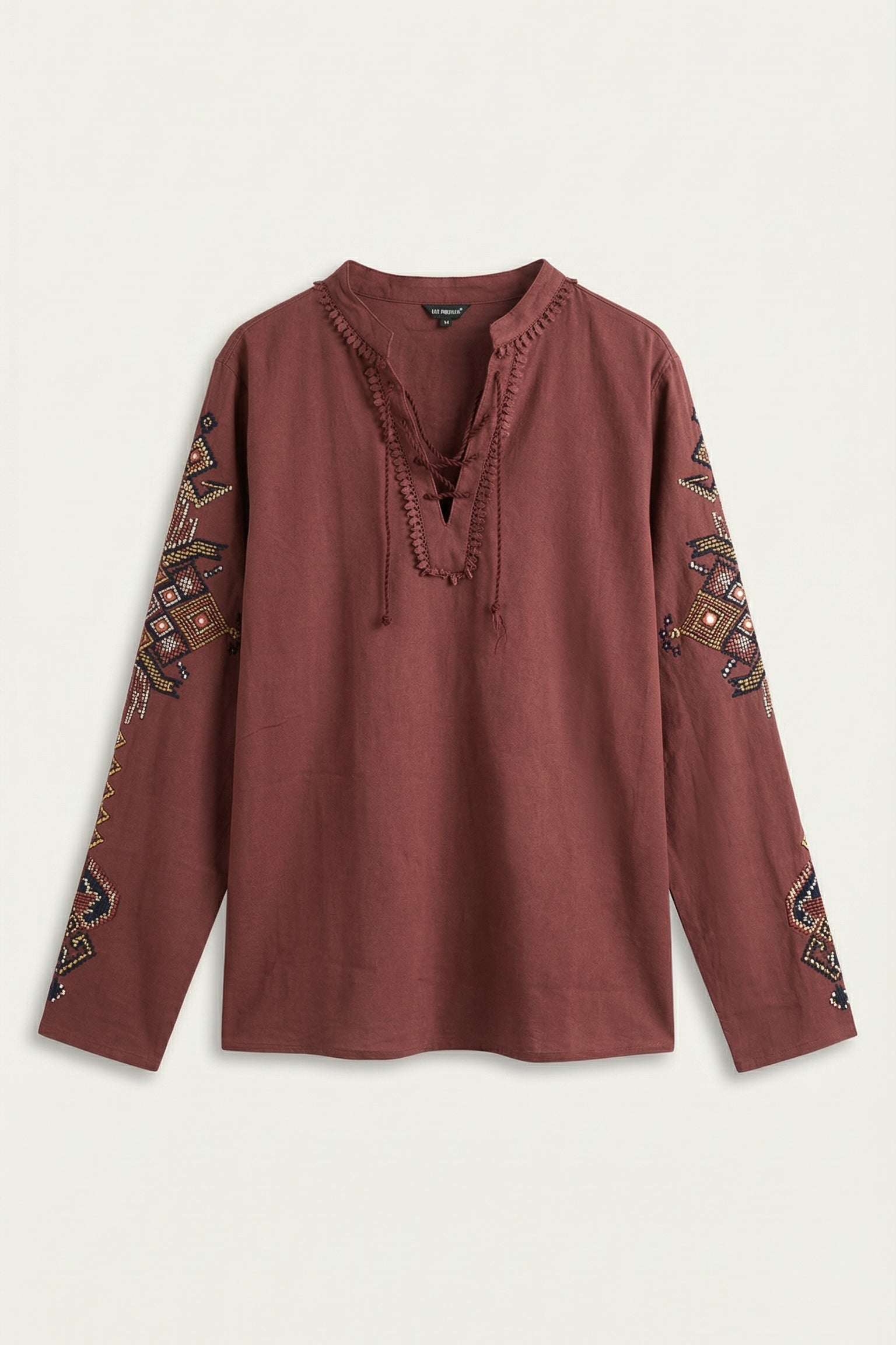 Brown blouse with intricate patterns on sleeves against a light background