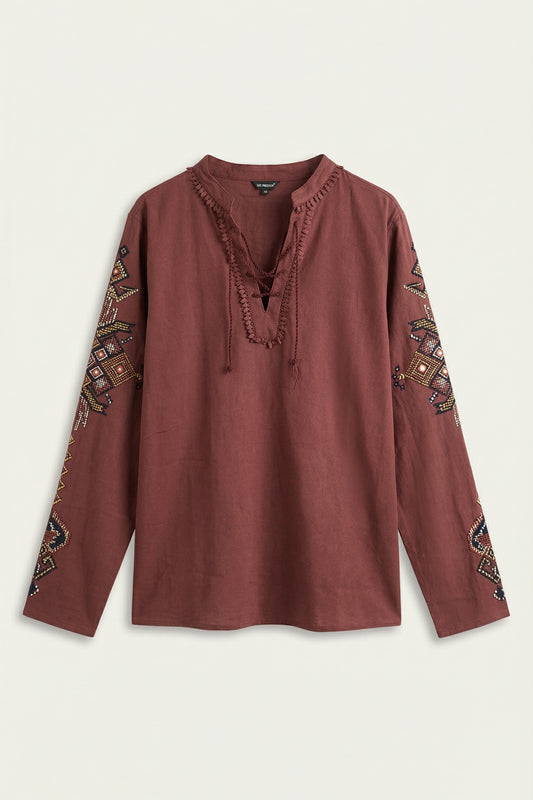 Brown blouse with intricate patterns on sleeves against a light background