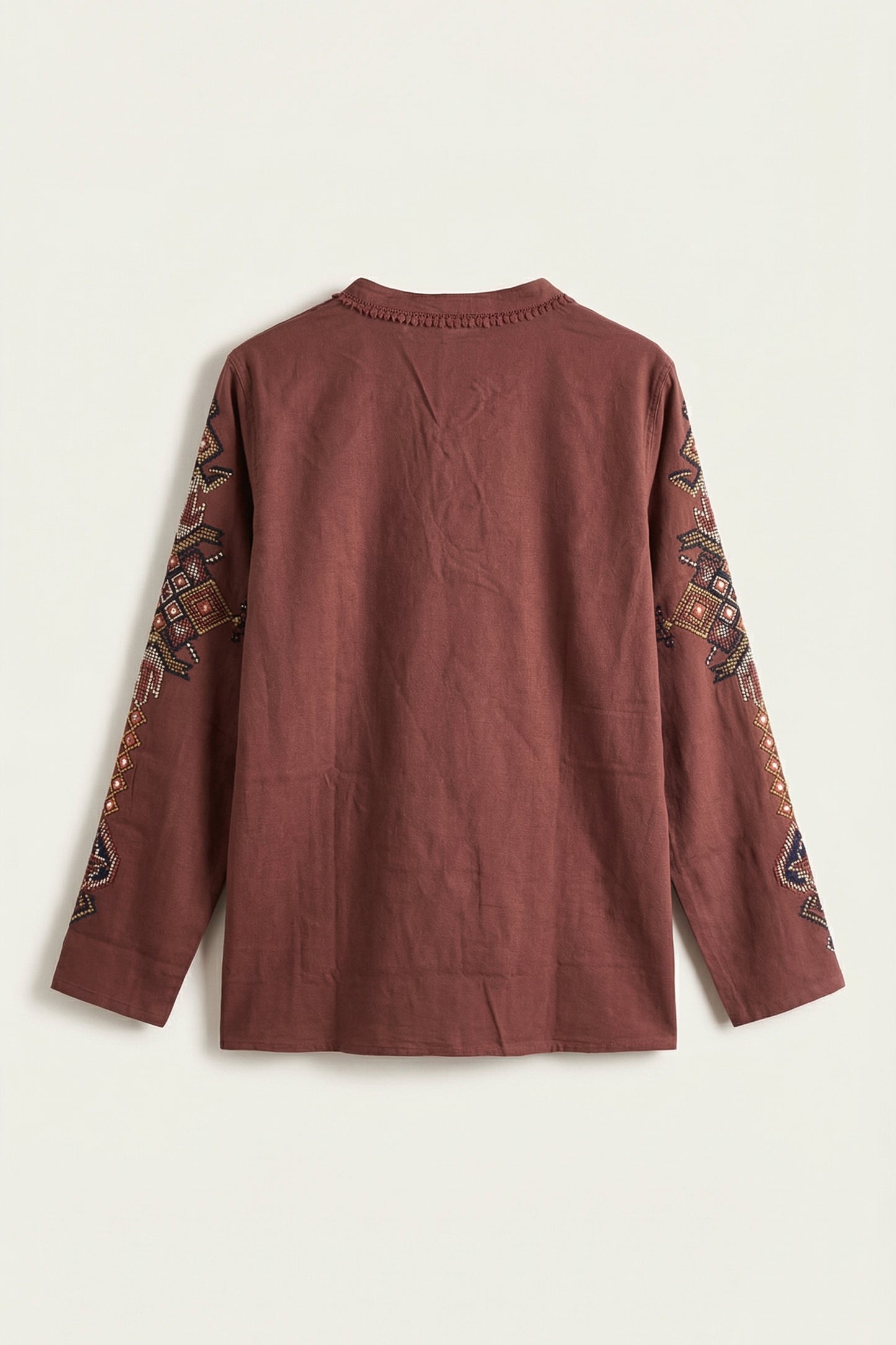 Brown long-sleeve top with intricate patterns on sleeves against a white background