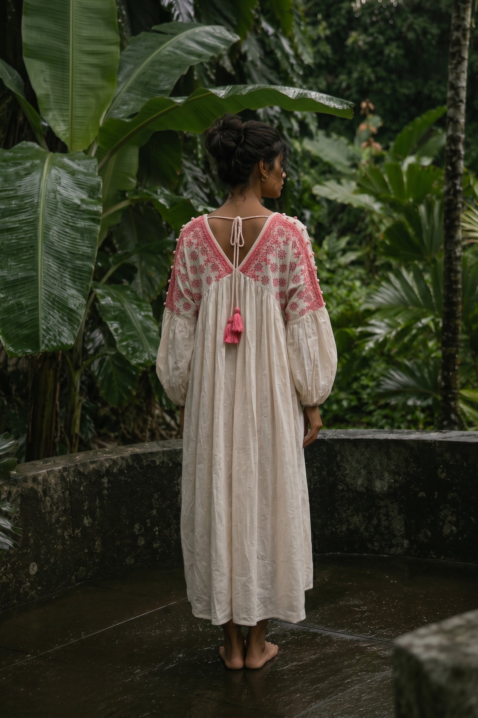 Woman in a white dress with pink accents standing in a tropical setting