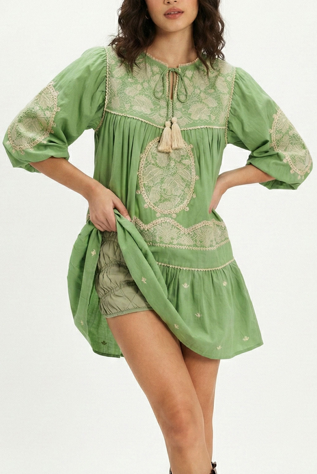 Woman wearing a green dress with lace details on a white background