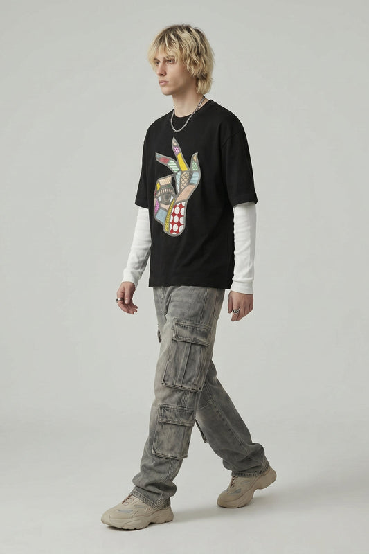 Person wearing a black graphic t-shirt, light gray cargo pants, and beige shoes on a plain background