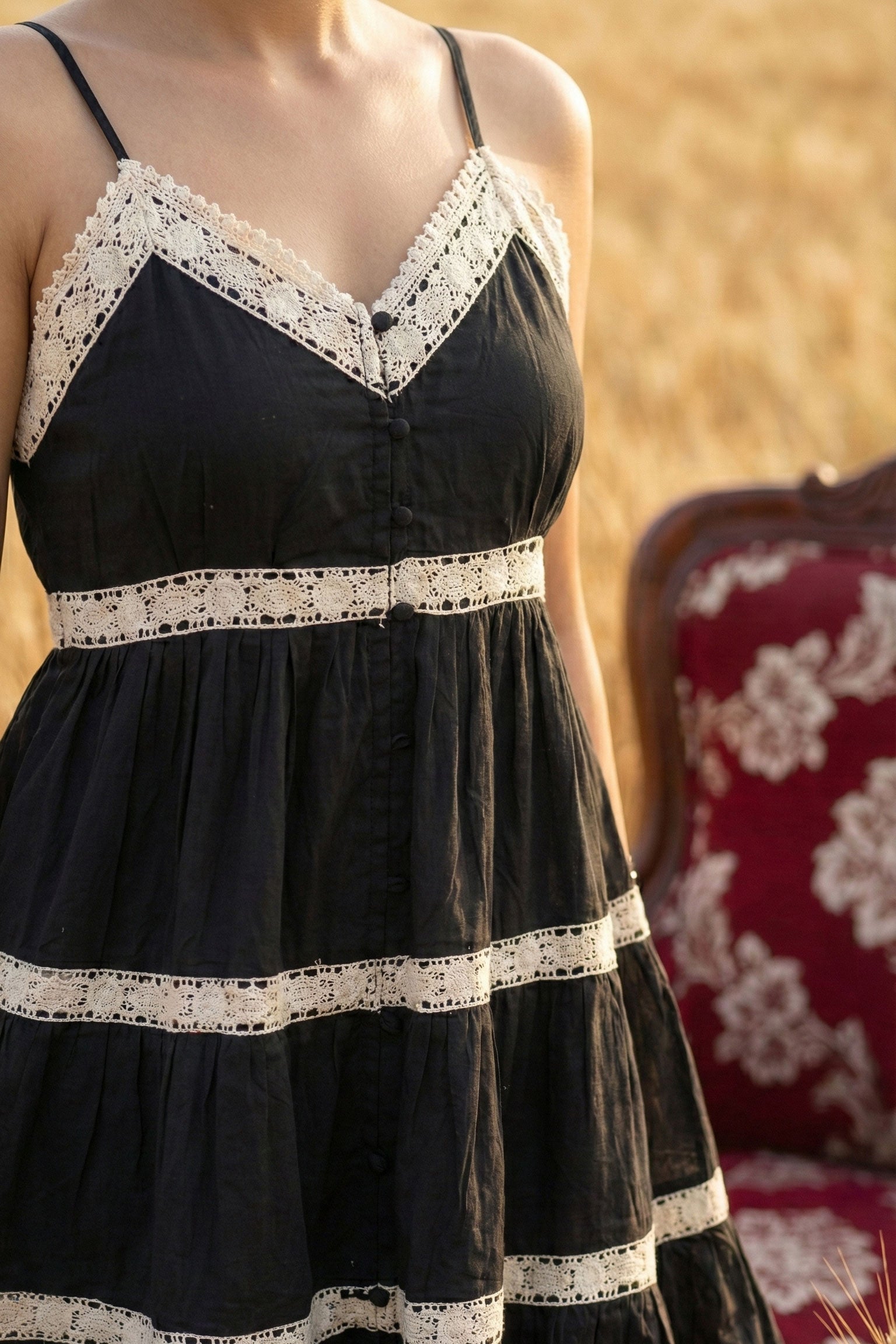 Black dress with white lace details worn by a person, with a blurred background.