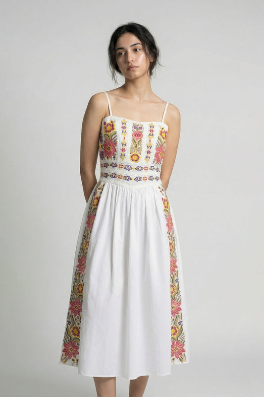 Woman wearing a white dress with colorful floral patterns on a plain background