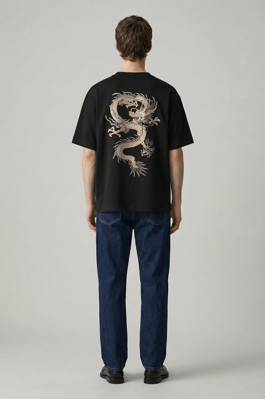 Person wearing a black t-shirt with a dragon design on the back, standing against a plain background.