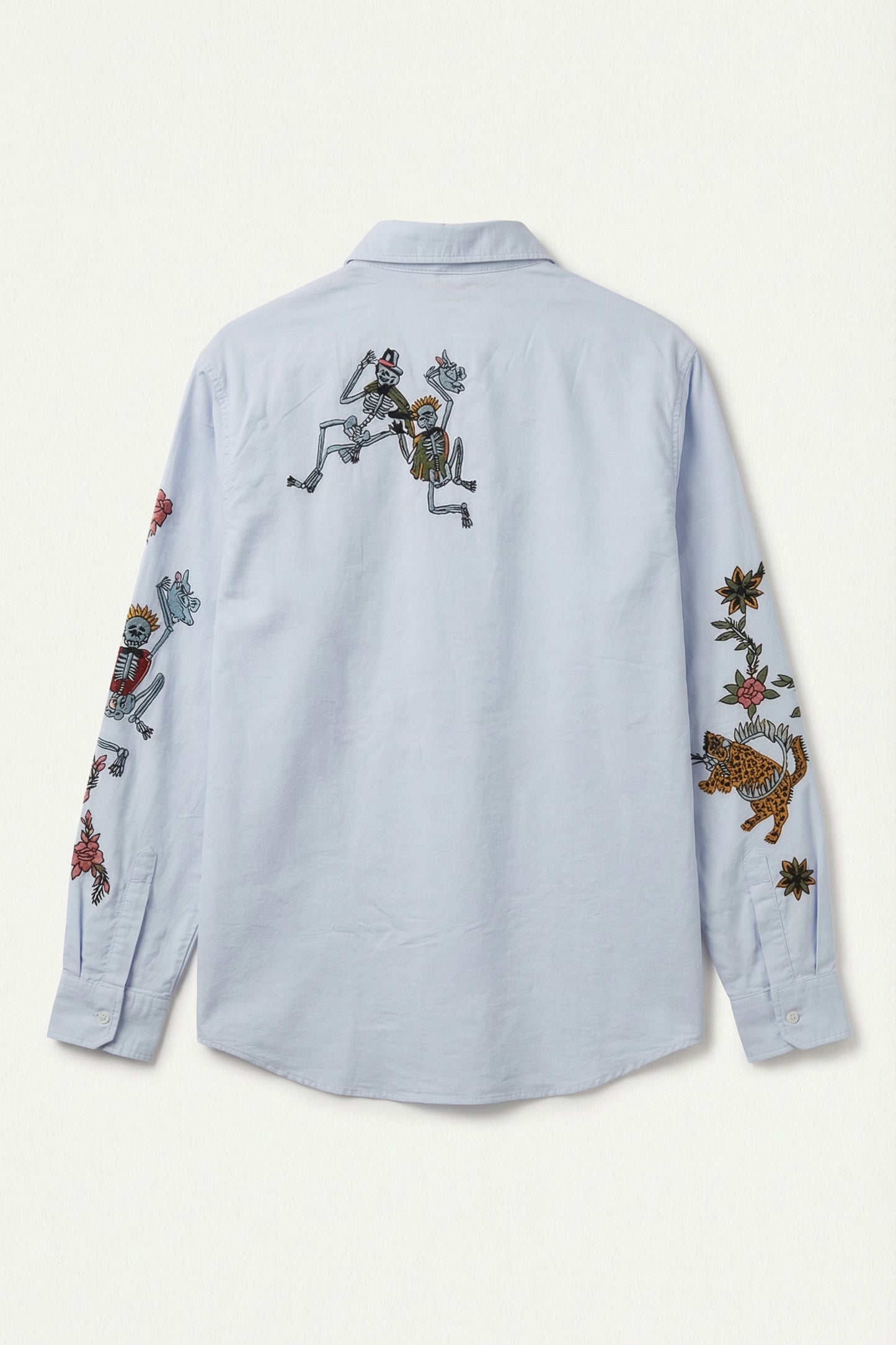 Light blue shirt with colorful embroidered designs on a white background