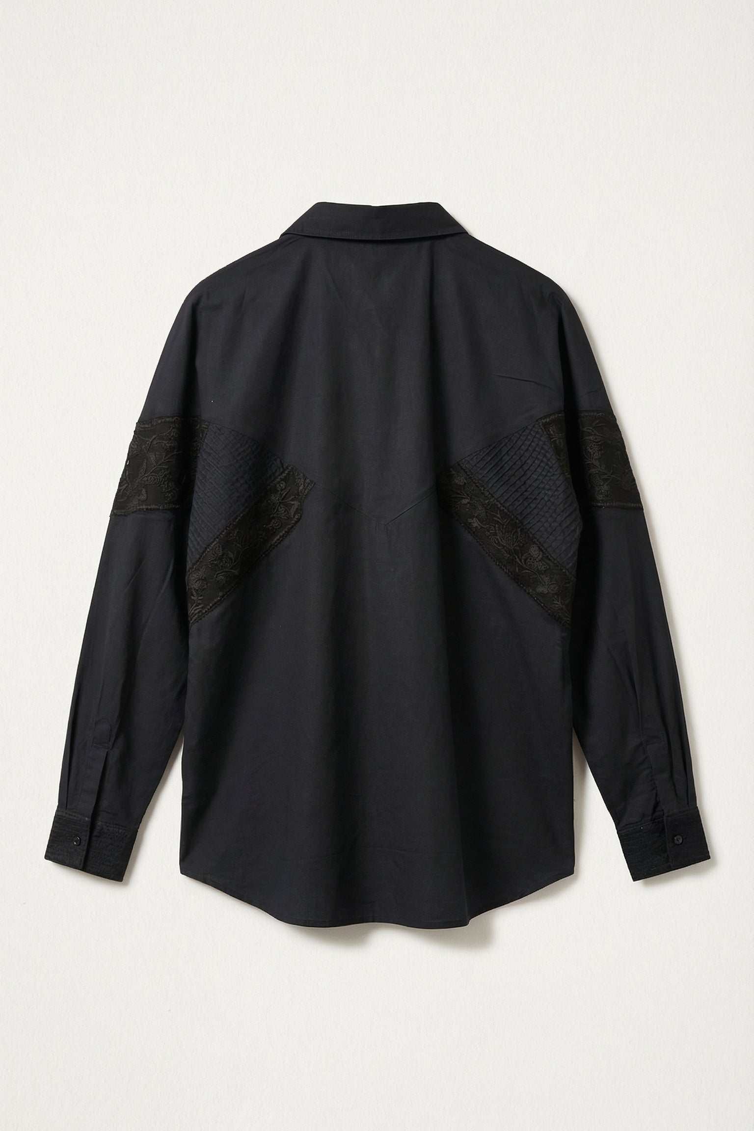 Black shirt with patch details on a light gray background