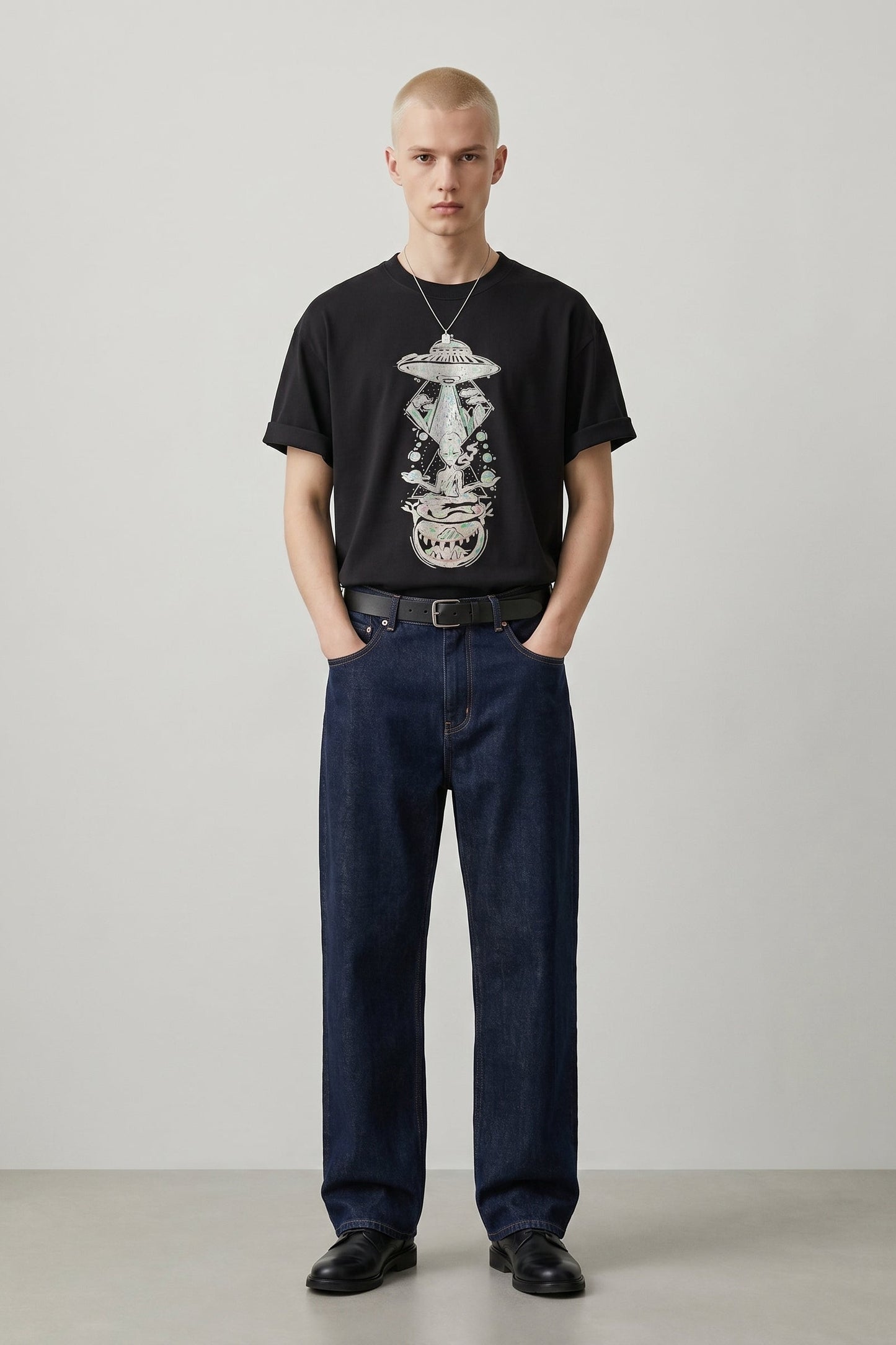Man wearing a black t-shirt with a graphic design and dark jeans against a plain background