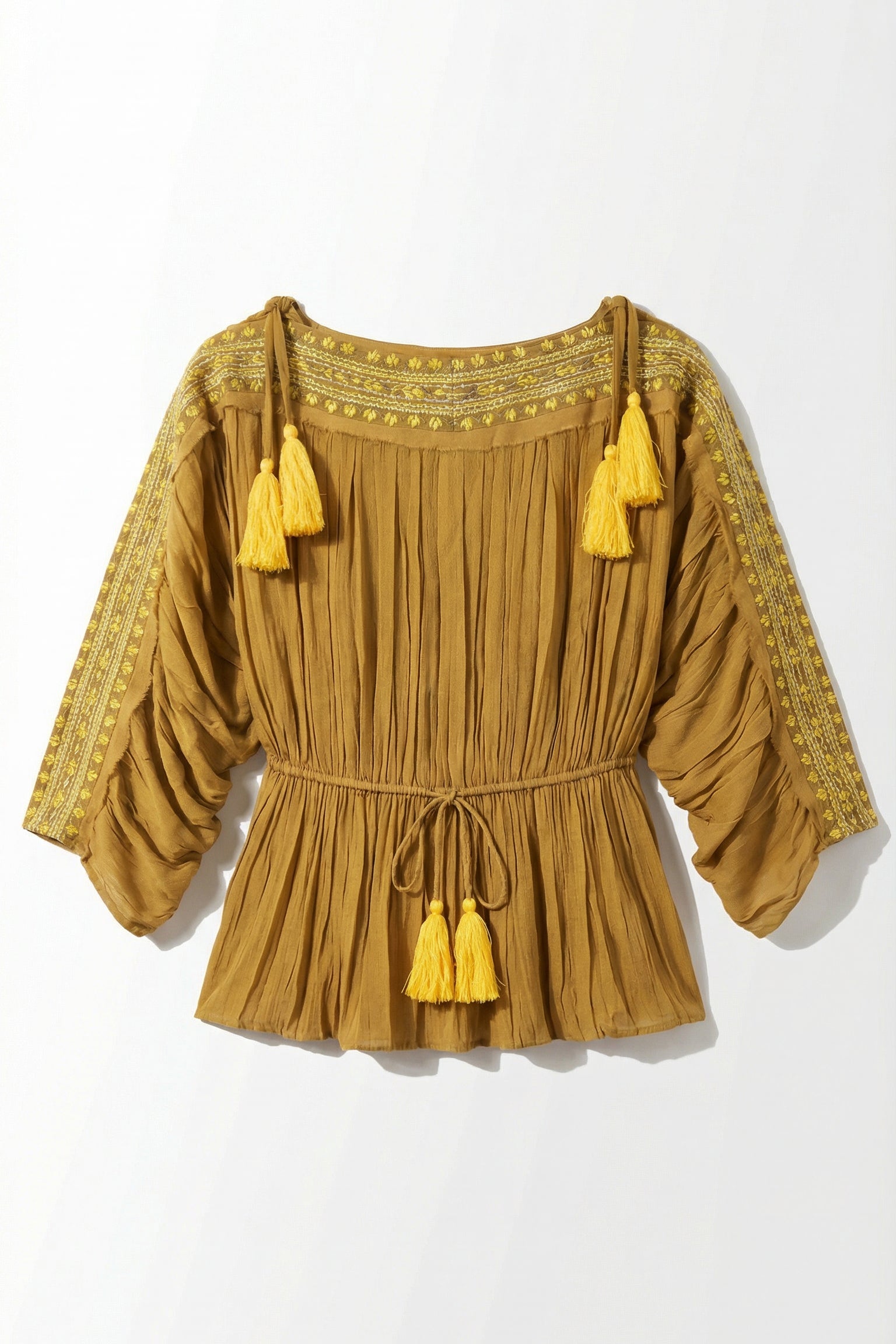 Mustard yellow blouse with tassels on a white background