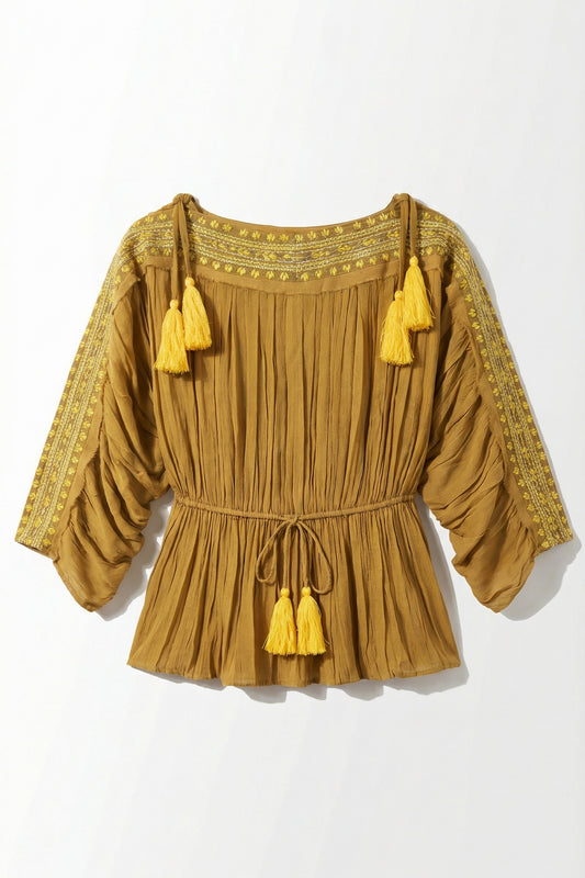 Mustard yellow blouse with tassels on a white background