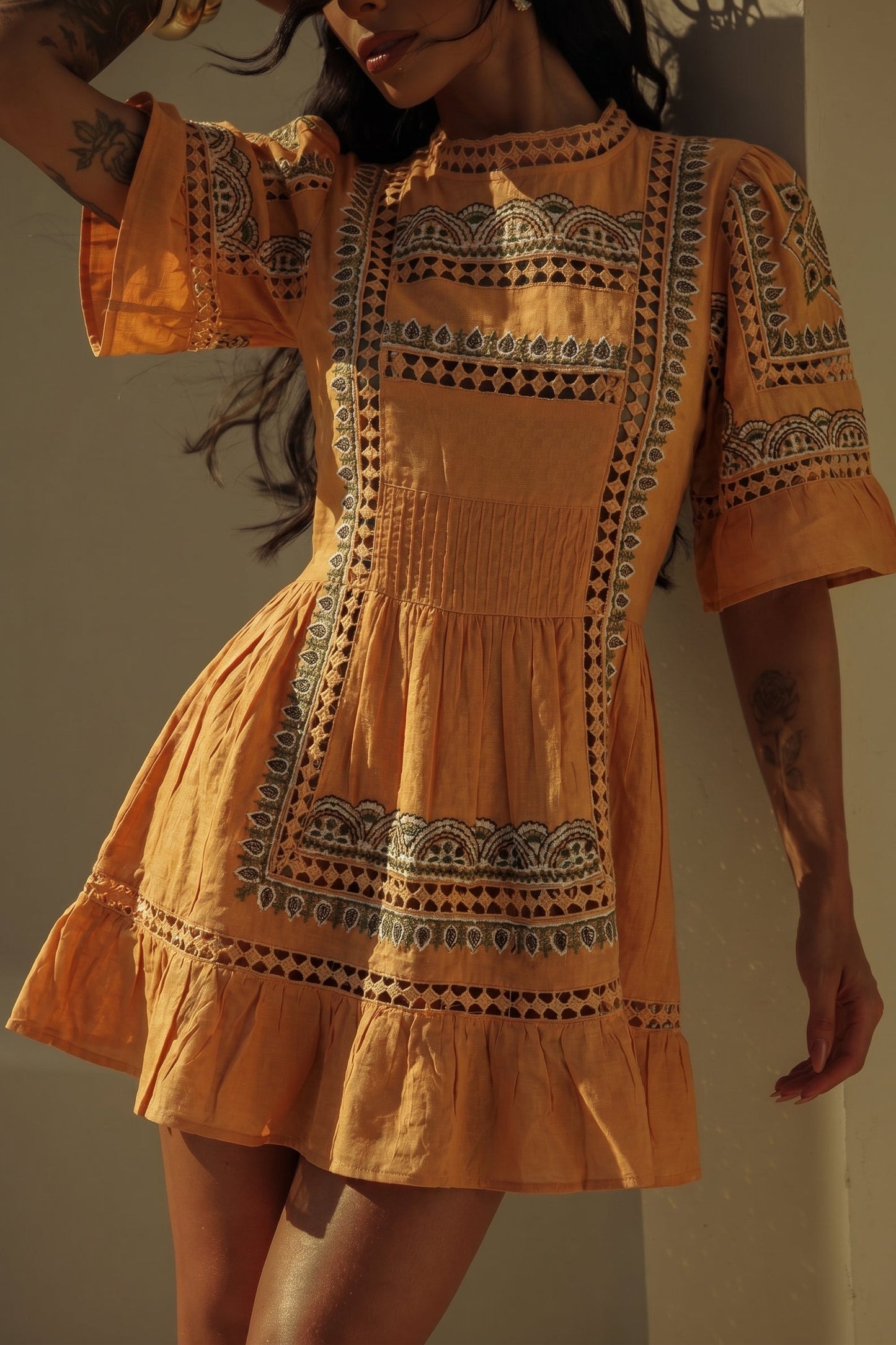 Woman wearing a mustard yellow dress with intricate patterns against a neutral background